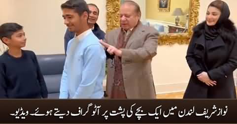 Nawaz Sharif signing an autograph on the back of a child in London